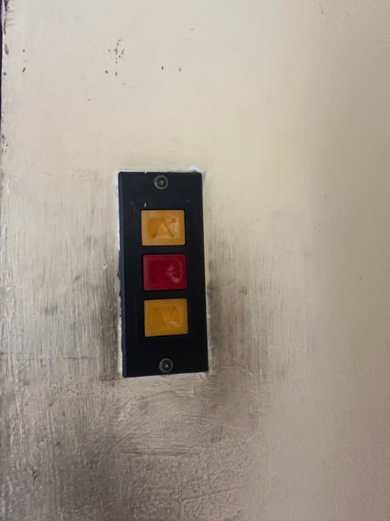 Cận cảnh ba nút: vàng cam mũi tên lên, đỏ dừng ở giữa, vàng cam mũi tên xuống